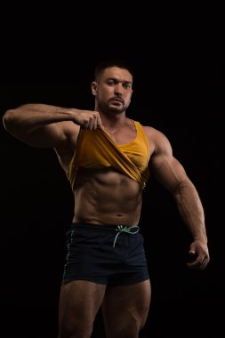 siyah bir arka plan üzerinde poz yakışıklı kaslı vücut geliştirmeci
