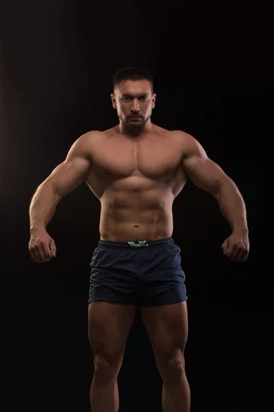 Knappe gespierde bodybuilder poseren op een zwarte achtergrond — Stockfoto