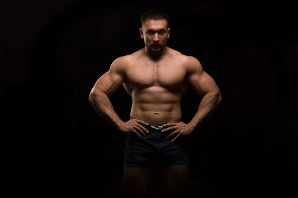 Stilig muskulös bodybuilder poserar på en svart bakgrund — Stockfoto