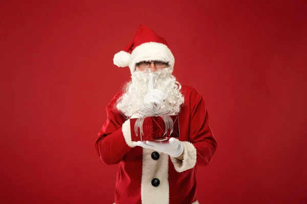 Санта Клаус з подарунком на червоному тлі — стокове фото
