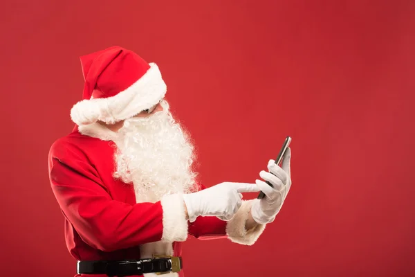 Santa Claus con una tableta sobre un fondo rojo — Foto de Stock