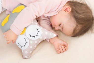 Güzel uyuyor kız bebek, yürümeye başlayan çocuk ile bir baykuş oyuncak close-up portre