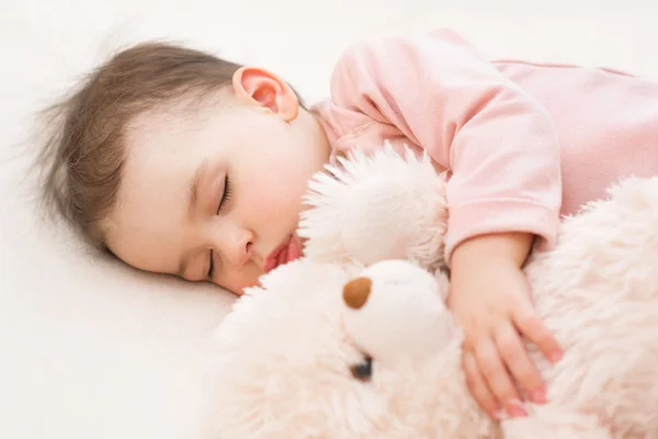Gyönyörű baba kisgyermek lány alszik az ágyon egy bolyhos mackó közelről portréja — Stock Fotó