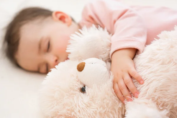 Alvó gyönyörű baba kisgyermek lány az ágyon, közeli portré egy bolyhos mackó — Stock Fotó