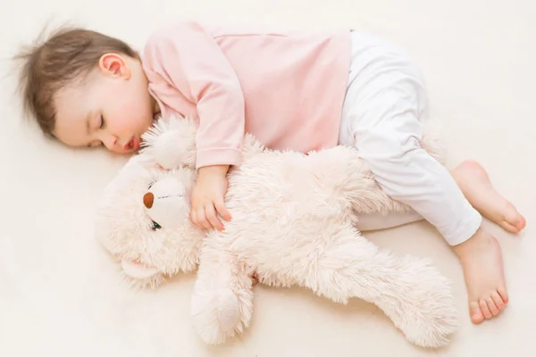 Κορίτσι μικρό παιδί ύπνου όμορφο μωρό με ένα χνουδωτό αρκουδάκι στο κρεβάτι — Φωτογραφία Αρχείου