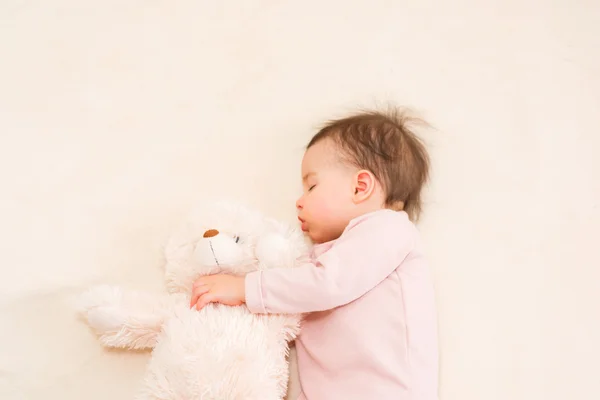 Increíble retrato de dormir hermosa niña bebé con un oso de peluche esponjoso en la cama — Foto de Stock