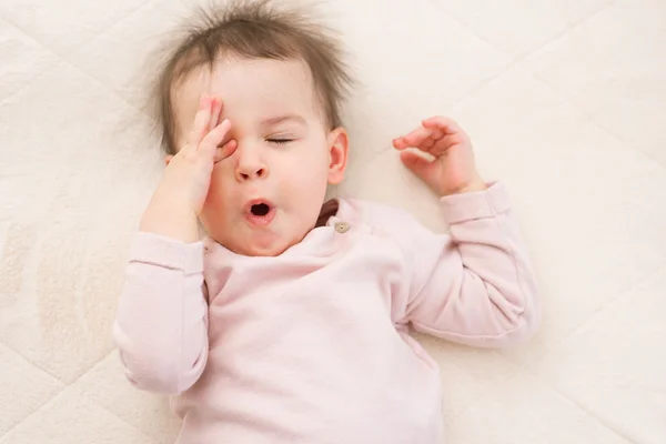 Yawning and sleeping beautiful baby toddler on the bed. Portrait — Stock Photo, Image