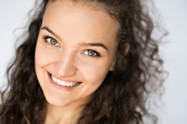 Genç esmer kadının şaşırtıcı yeşil gözlü gülümseyen güzel yakın çekim portre