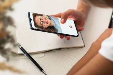 Görüntülü konuşma yapan bir kız. İş kadını iş arkadaşıyla çevrimiçi toplantı sırasında görüntülü konferansta. Genç bir kadın elinde bir cep telefonu tutuyor ve arkadaşıyla görüntülü konuşma yapıyor.