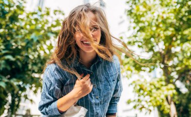 Güneşli bir günde üniversiteye giden sırt çantalı güzel bir genç kadının açık hava portresi. Şehir caddesinde yürüyen mutlu üniversite öğrencisi..