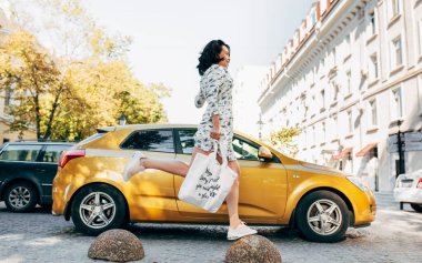 Sokakta markete elinde bir çantayla giden güzel bir genç kadının yatay görüntüsü. Güneşli bir günde çekici bir kadın tekrar kullanılabilir bir tekstil torbasıyla poz veriyor..