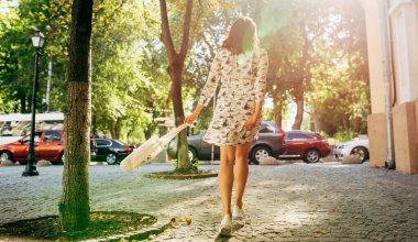 Şehir caddesinde bir çevre çantasıyla yürüyen güzel bir genç kadının tam boy dikiz manzarası. Güneşli bir günde tekrar kullanılabilir bir tekstil torbasıyla poz veren güzel kız..