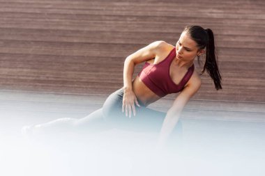 Açık havada uzanan sportif bir kadının yatay çekimi. Spor salonundaki kadın sabahları biraz esneme egzersizi yapıyor..