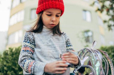 Kırmızı şapkalı şirin bir kız dışarıda oturuyor.. 