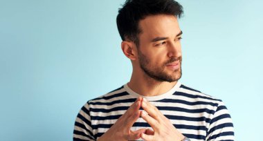 İlan için poz veren yakışıklı bir delikanlının yakın çekimi. Erkeğin beyaz mavi duvara karşı düşünceli bir ifadesi var..