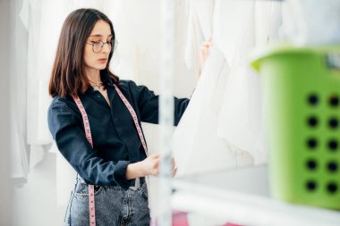 Bir moda tasarımcısının yatay görüntüsü çalışma alanındaki dikiş kalıplarına bakıyor. Genç bayan işyeri sahibi yaratıcı ofisinde çalışıyor.. 