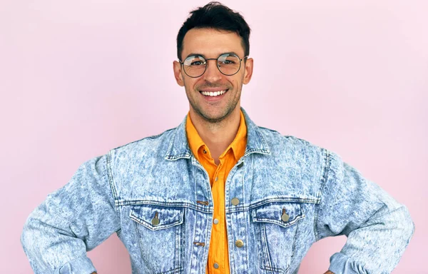 若い幸せな笑顔男性でジーンズジャケット 黄色のシャツと透明眼鏡 カメラを見て 広く笑顔 ピンクの背景に立って — ストック写真