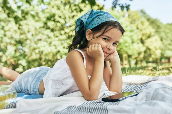 Smiling Little Girl Looking Camera Lying Blanket Playing Device Park — Stock Photo, Image