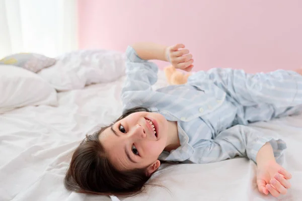파자마를 줄무늬 소녀는 웃으면서 카메라를 바라보며 침대에 아이는 아침에 즐거운 — 스톡 사진
