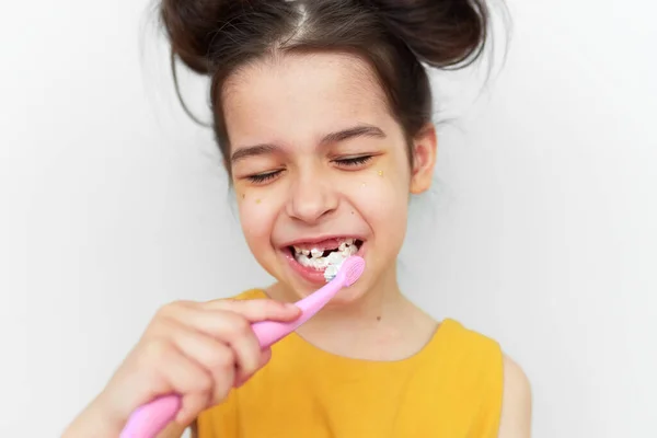 黄色のドレスブラッシング歯の喜びの少女は 灰色の背景に隔離された最初の永久的なモル成長と空の空間を示しています 子供は乳歯を失い歯を磨く準備ができています — ストック写真