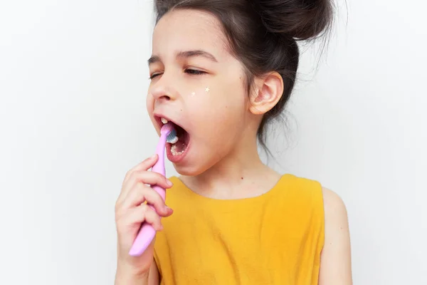 灰色のスタジオの背景に孤立した小さな女の子の歯をブラッシングの肖像画 かなりの子供は歯を磨く準備ができている 歯医者の日 歯のケア 医療の概念 — ストック写真