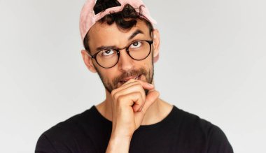 Şüpheli bir gencin yakın plan portresi ne yapacağını bilmiyor, şık siyah tişört, şeffaf gözlük ve pembe şapka giyiyor. Erkek ifadesini karıştırdı.