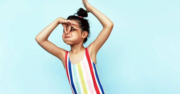 一个顽皮的小女孩抱着鼻子游泳 在蓝色的背景下摆出室内姿势 一个穿着五颜六色泳衣的可爱小女孩托着鼻子在游泳池里学游泳 — 图库照片