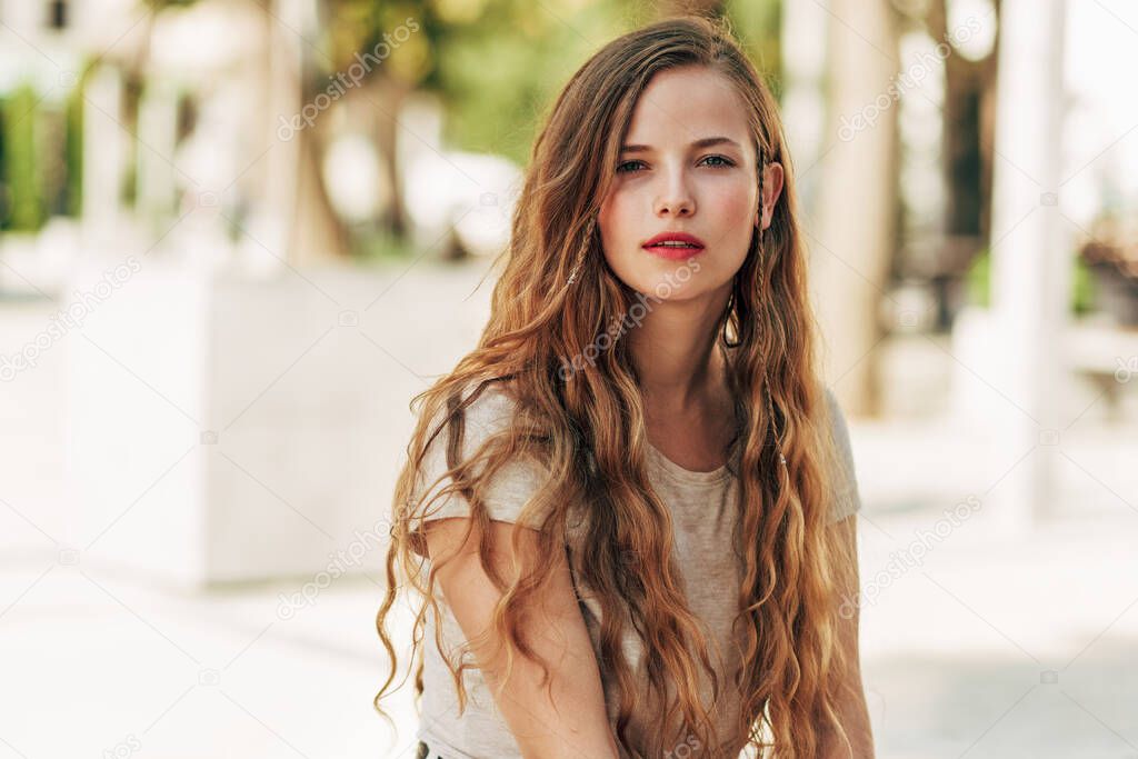 Portarit of a beautiful Caucasian young woman resting on the street. A beautiful female has a joyful expression while sitting outdoors. Mental health concept.