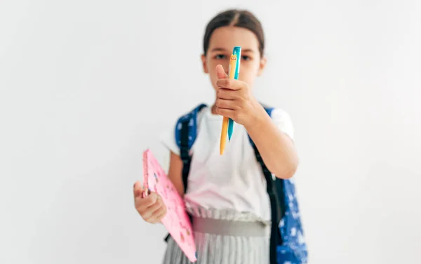 カメラに直接焦点を当てて鉛筆を示すバックパックを持つ少女の肖像画 学校に戻るバックパック付きの学校の子供 — ストック写真