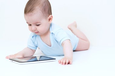 Beyaz yerde yatarken tablet ile mutlu bebek