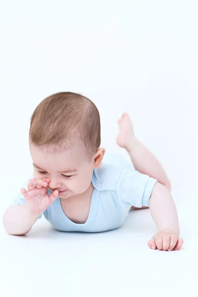 Sorridente adorabile bambino sul pavimento bianco guardando giù con mano — Foto Stock