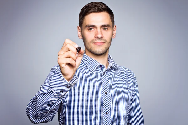 Hombre de negocios señalando algo con marcador sobre fondo gris —  Fotos de Stock