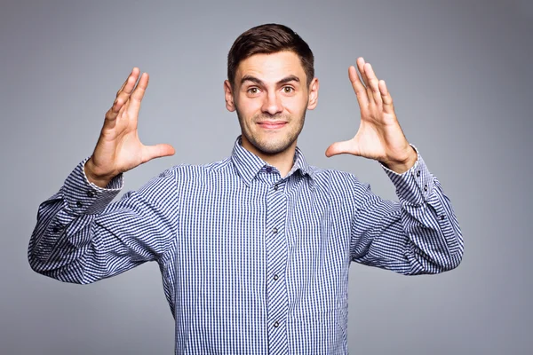 Hombre de negocios mostrando algo sobre fondo gris — Foto de Stock