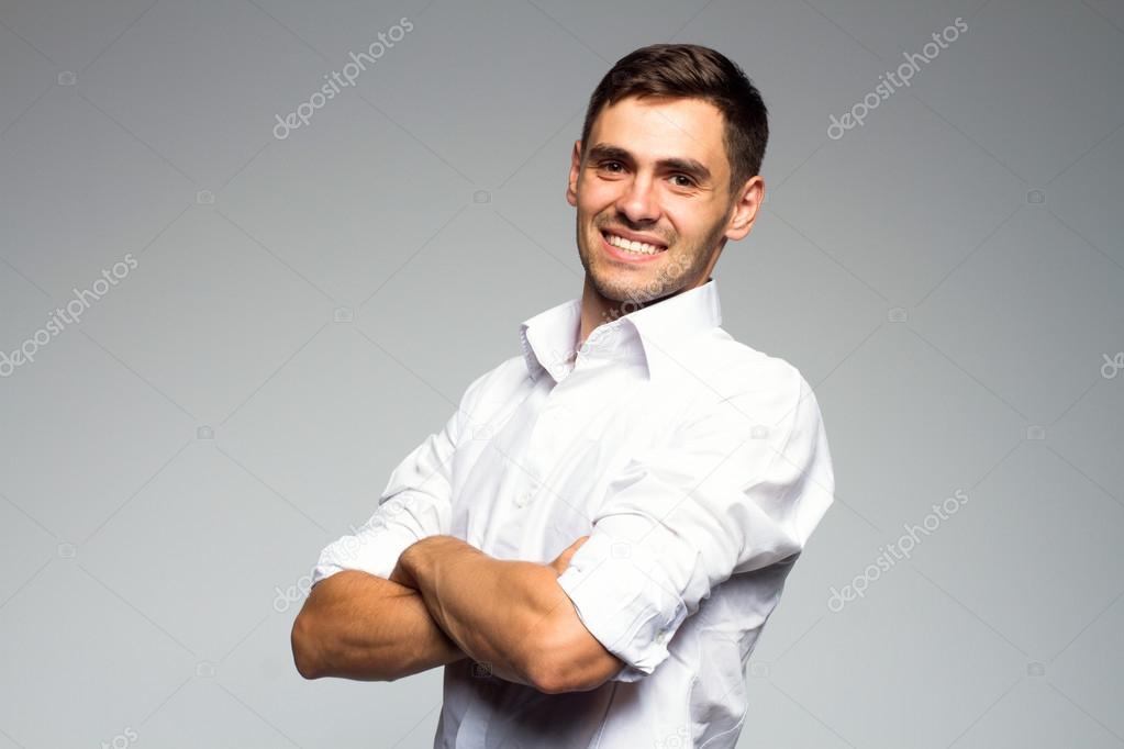 Portrait of young smiling happy business man, isolated over gray background