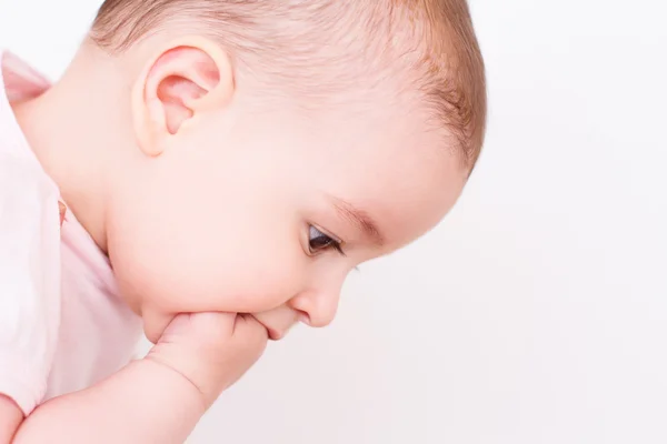 Pensant belle fille bébé regarder vers le bas avec la main dans la bouche sur blanc — Photo