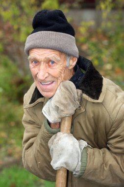 Onun elinde bir kürek ile gülümseyen yaşlı adam