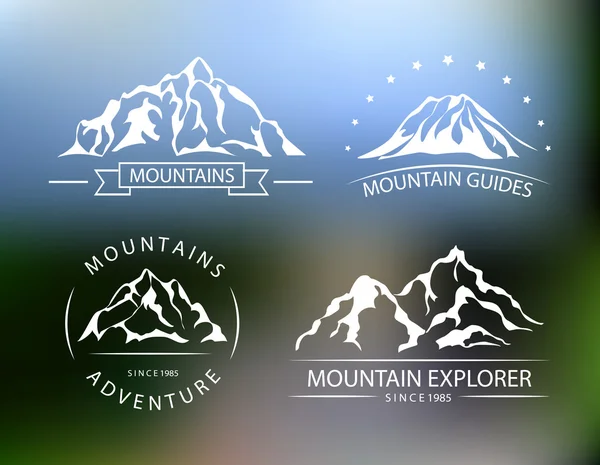 Emblemas vectoriales de montaña en el fondo borroso . — Archivo Imágenes Vectoriales
