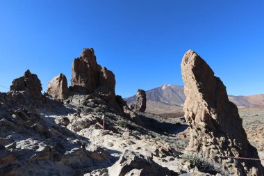 Ön planda kaya oluşumu ve arka planda volkanik dağ manzarası, lav ve erozyon tarafından şekillendirilen kurak arazi, açık gökyüzü ve gün ışığı, Tenerife adası, Kanarya Adaları, İspanya