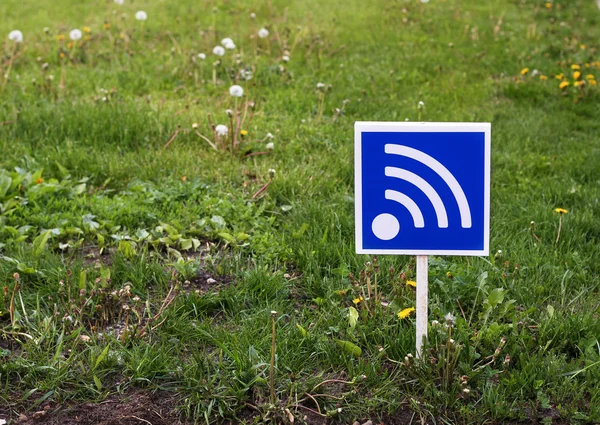 RSS bir yeşil çimenlerin üzerinde oturum açın. Ücretsiz Wi-Fi erkek. Wi-fi işareti. 