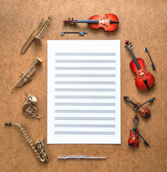 Uppsättning av fem gyllene mässing vind och fyra sträng musikalisk orkester instrument: saxofon, trumpet, valthorn, trombon, violin, cello, kontrabas, viola. Sheet music ligger mellan dem.. — Stockfoto