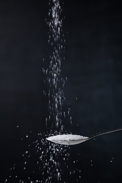 Pile of white sugar in a teaspoon