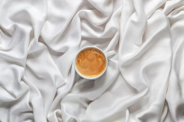 흰색 흰색 실크 직물에 커피 한잔. 웃는 얼굴의 형태로 거품으로 에스프레소 커피 컵. 상위 뷰. — 스톡 사진