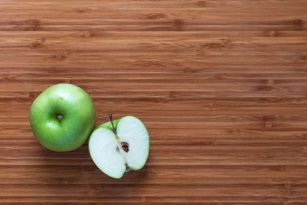 Taze olgun yeşil elma Granny Smith: bütün ve bir ahşap kesme tahtası üzerinde yarısında dilimlenmiş. Doğa meyve kavramı. Sağlıklı beslenme Temalar için arka plan.
