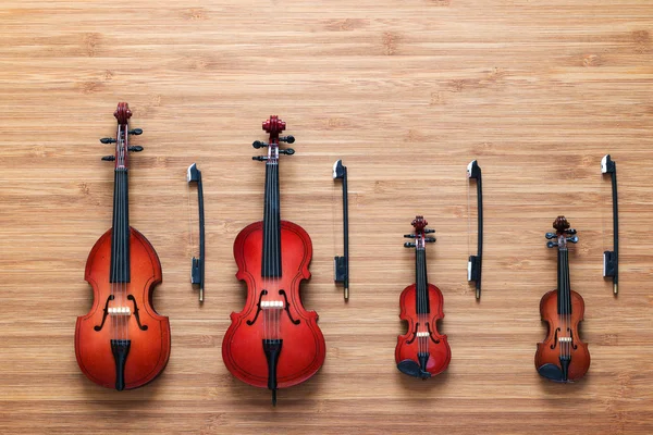 Dört oyuncak dize müzikal orkestra araç: keman, viyolonsel, kontrbas, ahşap arka plan viola. Yaylı çalgılar dörtlüsü. Müzik konsepti. — Stok fotoğraf