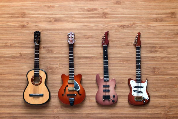Cztery różne elektryczne i akustyczne gitary na drewniane tła. Zabawka gitary. Koncepcja muzyki. — Zdjęcie stockowe