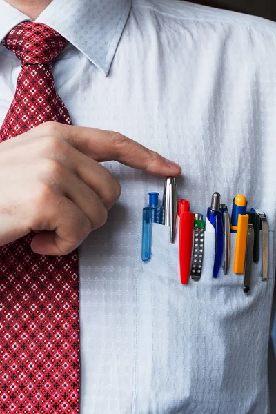 El elegante hombre de negocios elegante manteniendo una gran cantidad de bolígrafos de colores en su bolsillo del pecho . — Foto de Stock