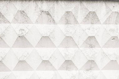İnce çatlaklar ve kusurlarla yinelenen geometrik bir desen içeren desenli beton bariyerin yakın plan görüntüsü