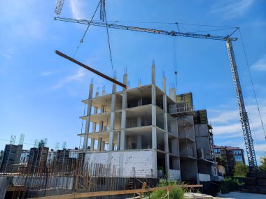 Uzun bir vinç inşaat halindeki bir binaya yerleştirilmesi için çelik kirişi kaldırıyor.