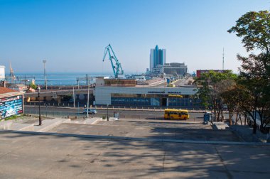 Odesa, Ukrayna. 3 Ekim 2016. Etiketli modern Odesa Deniz Limanı terminal binası, arka planda büyük vinçler ve yanından geçen sarı bir minibüsle görülebilir.