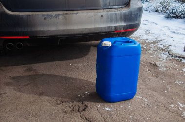 Açık mavi plastik bir konteynır, siyah, tozlu bir arabanın arkasında, soğuk havaya ya da bir yolculuğa hazırlanmayı öneriyor.